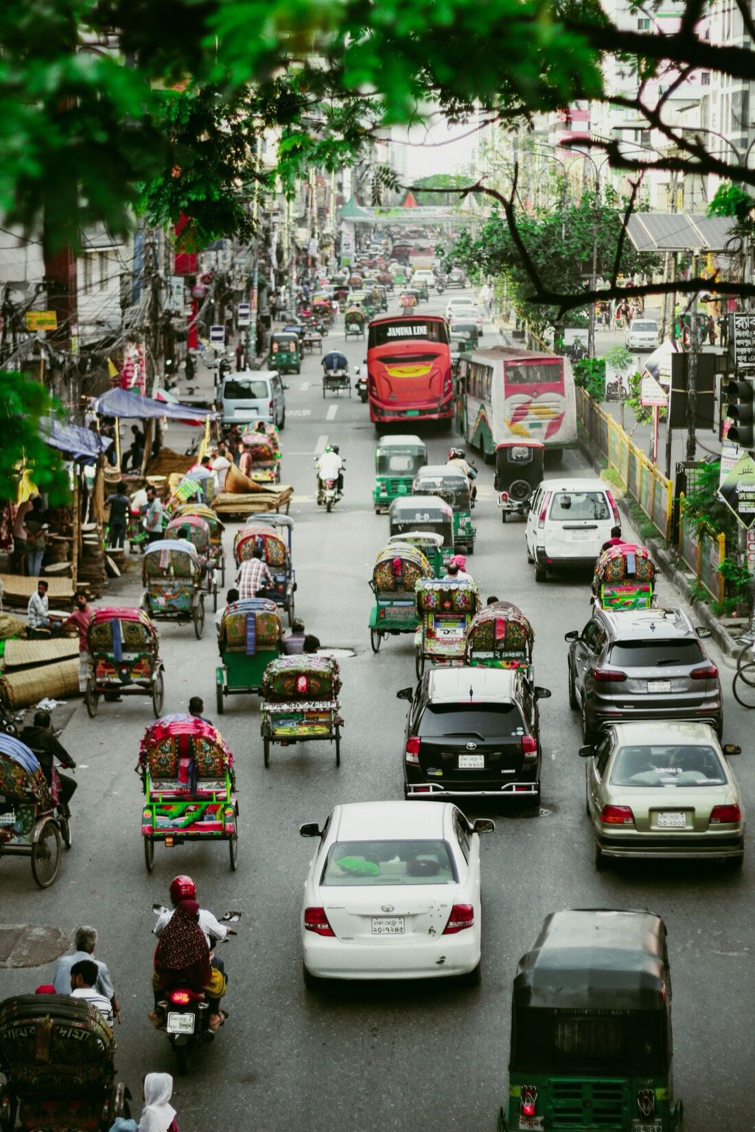 A Dhaka street at working pace — cycle rickshaws and traffic.