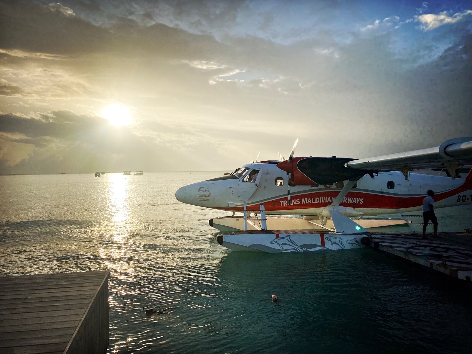 A Trans Maldivian Airways seaplane at sunset, moored at the dock — the iconic Maldives transfer experience
