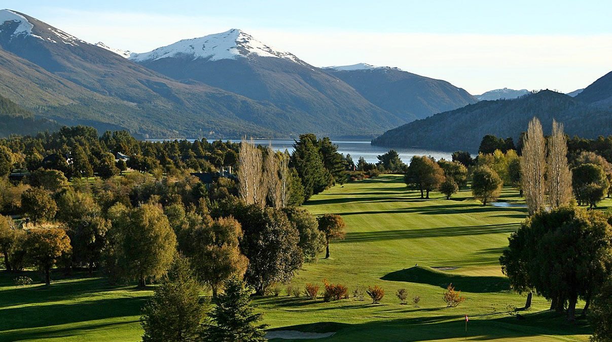 A golf course beside a lake in Patagonia, with snow on the mountains