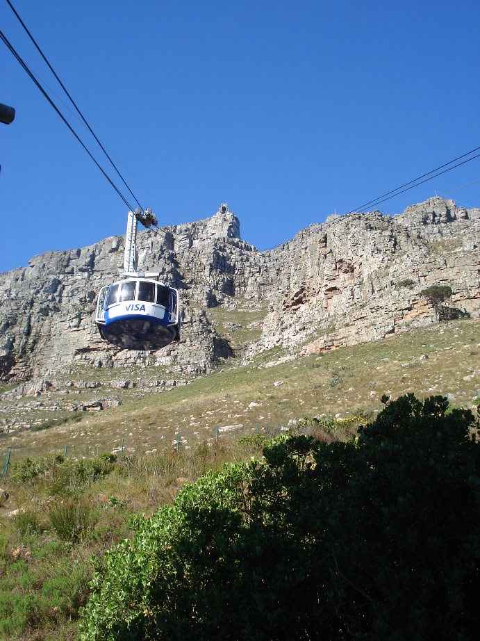 Table Mountain cable car ascending the mountain face on a clear blue day